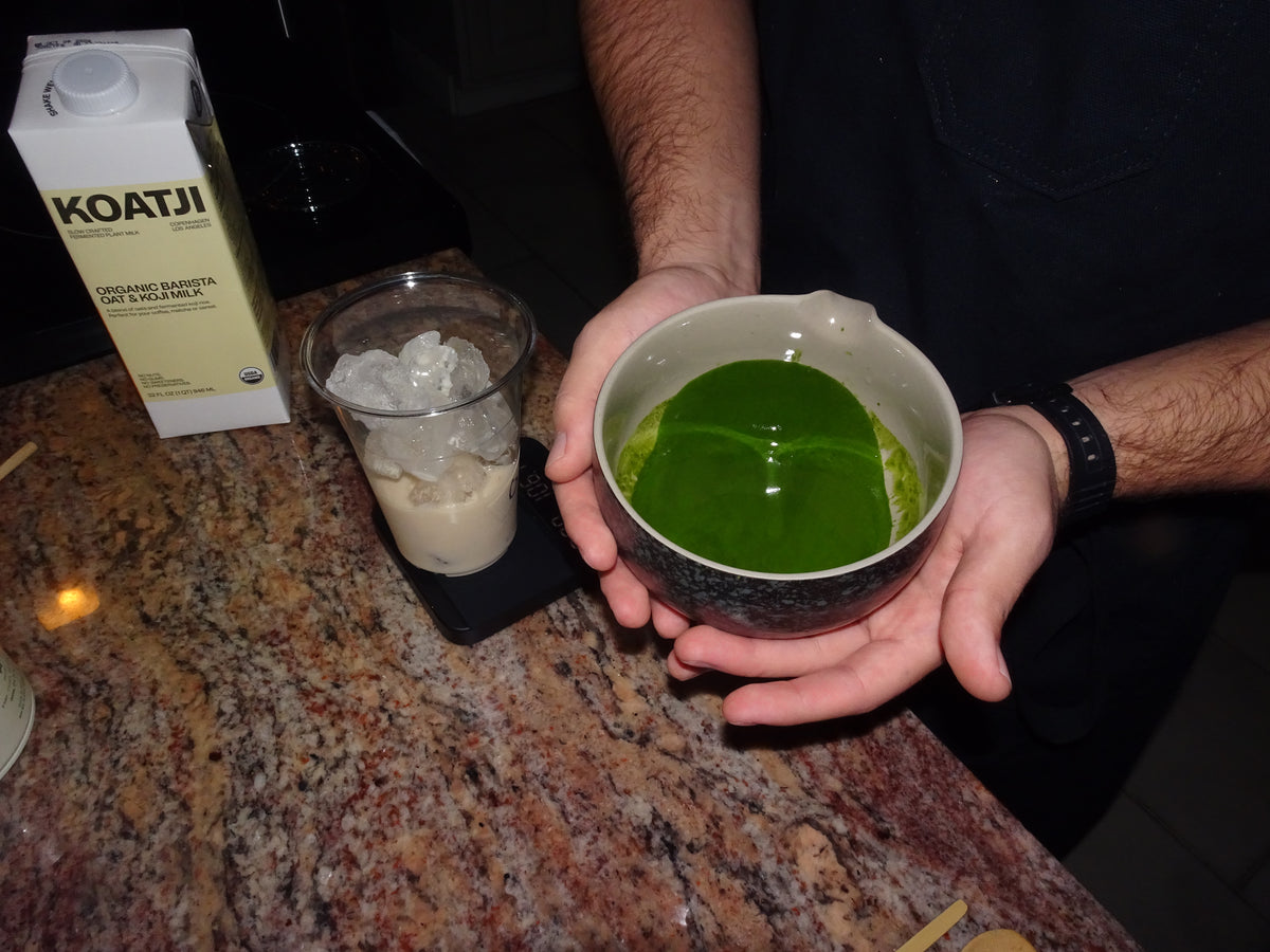 Hands holding a bowl of freshly whisked matcha